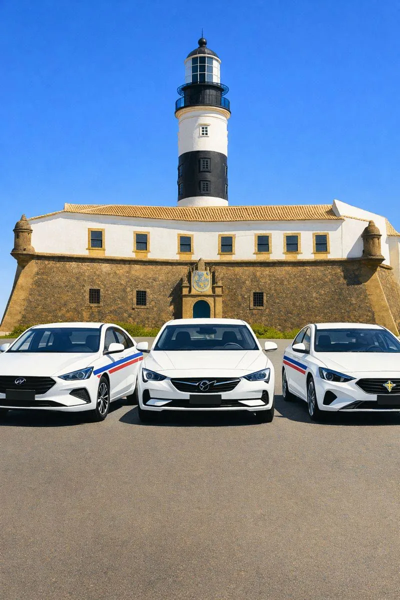 Três táxis do Taxi Bahia estacionados em frente ao Farol da Barra