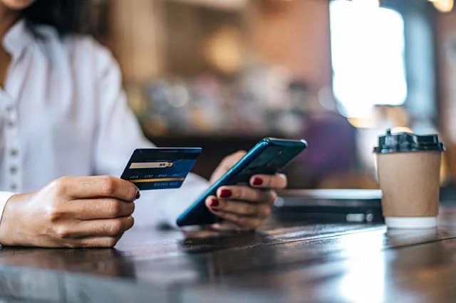 Pessoa pagando com cartão e celular na mão